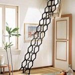Escalera de ático desplegable con patrón de panel que se despliega en una buhardilla luminosa, bien decorada, con plantas y obras.
