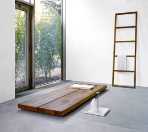 Una habitación de estilo monocromo con una cama de plataforma baja de madera adyacente a una gran ventana y una simple escalera de madera contra la pared.