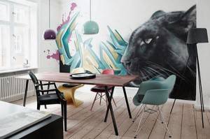 Una moderna sala de comedor con una mesa de madera, sillas eclécticas y un sorprendente mural en la pared de una pantera negra con elementos abstractos de color.