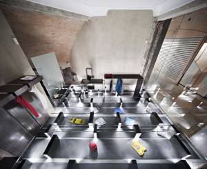 Una vista aérea de una gran mesa de futbolín del tamaño de una habitación con ropa y artículos encima, lo que indica un uso poco convencional de la mesa de juego en un espacio con paredes de ladrillo y una decoración moderna para el Con