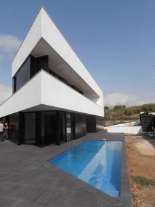 Casa moderna de dos pisos con un exterior blanco con formas geométricas y una piscina en primer plano, construida en 2013.