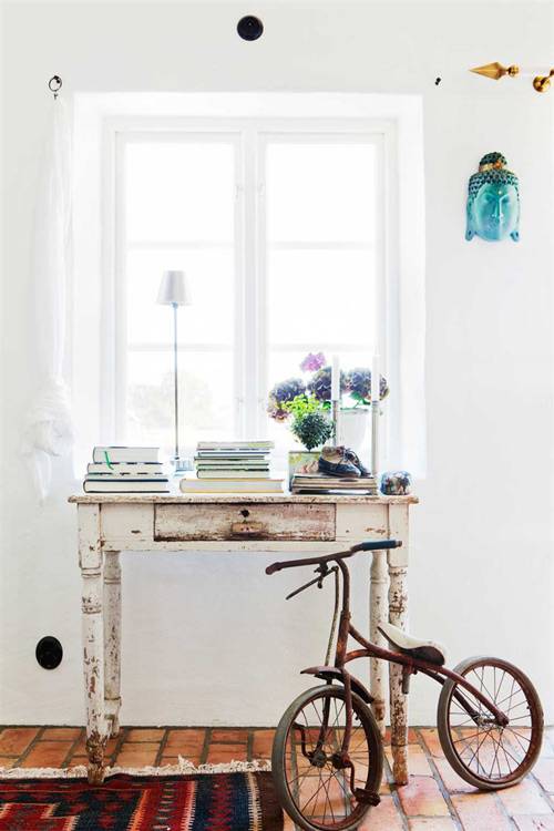 Una consola bajo la ventana con varios libros, una lámpara, crea un rincón muy bonito.