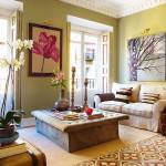 Una acogedora sala de estar con suelo hundido, con un sofá beige, una alfombra estampada y una variedad de elementos decorativos que incluyen una gran mesa de café con libros, flores y obras de arte enmarcadas.