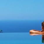 Una persona se relaja en una piscina infinita que da la impresión de fusionarse sin fin con el cielo.