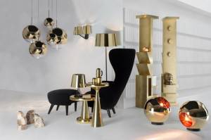 Una feria de Milán, interior elegante con un sillón negro, mesas decorativas doradas inspiradas en las últimas "Tendencias en dorado" y una variedad de accesorios de iluminación contemporáneos con acabados metálicos.