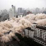 Una nube de polvo envuelve una calle de la ciudad durante el derribo de un edificio.