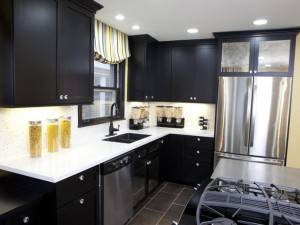 Una cocina moderna con gabinetes negros, encimeras blancas, electrodomésticos de acero inoxidable y una cortina de ventana estampada amarilla y