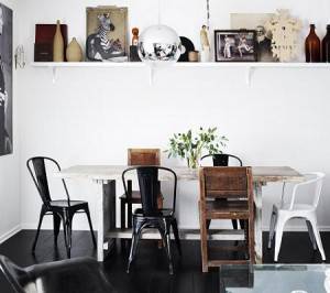 Una sala de comer que presenta una mezcla de elementos modernos y rústicos con una variedad de sillas diferentes alrededor de una mesa blanca de madera, decorada frente.