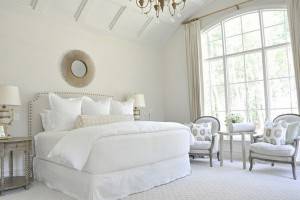 Una habitación luminosa y espaciosa con decoración de dormitorios, presentando una cama grande con ropa de cama blanca, dos sillas tapizadas con co
