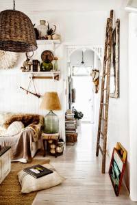 Una acogedora entrada de estilo rústico llena de encanto, decorada con objetos eclécticos, donde destaca una escalera apoyada contra la pared,