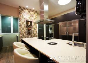 Una cocina moderna con sobres blancos, electrodomésticos de acero inoxidable y mosaicos decorativos en la pared, resaltando un estilo integral de Reforma.