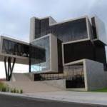 Una moderna estructura arquitectónica con formas geométricas y secciones voladizas, bajo un cielo nublado, diseñada por arquitectos destac.
