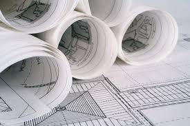 Planos arquitectónicos enrollados sobre planos de construcción planos, listos para el proyecto "Matar al arquitecto".