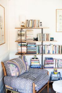 Una acogedora zona de lectura con un sillón estampado y un estante de madera repleto de libros, diseñada siguiendo las últimas tendencias en