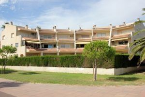Descripción: Una fila de casas adosadas con balcones en Cambrils, dispuestas frente a un cielo despejado, delimitadas por un seto bien cuid