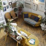 Una sala de estar de estilo bohemio con una decoración ecléctica, con una variedad de plantas, una variedad de obras de arte enmarcadas en las paredes y muebles vintage con textiles coloridos después de una "reformas viv".
