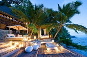 Descripción: Lujoso resort de playa con un espacio exterior chill out iluminado y cómodos asientos al anochecer.