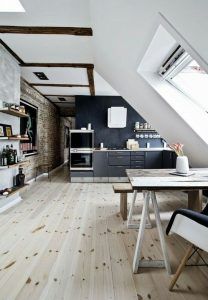 Una moderna cocina con techo inclinado, destacando vigas de madera a la vista, tragaluz, acentos de pared de ladrillo, y una combinación.