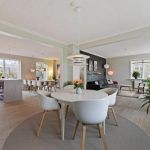 Un espacio luminoso y moderno de planta abierta con comedor, salón y cocina, con muebles contemporáneos "Menos es más" y grandes ventanales.