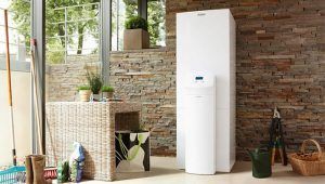 Un enfriador de agua de suelo colocado en una habitación bien iluminada con una pared decorativa de piedra, junto a muebles de mimbre y plantas de interior, integra la climatización del futuro.