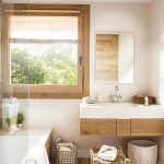 Un baño cómodo y moderno con detalles de madera natural, que cuenta con una cabina de ducha de cristal, un tocador de madera con una encimera.