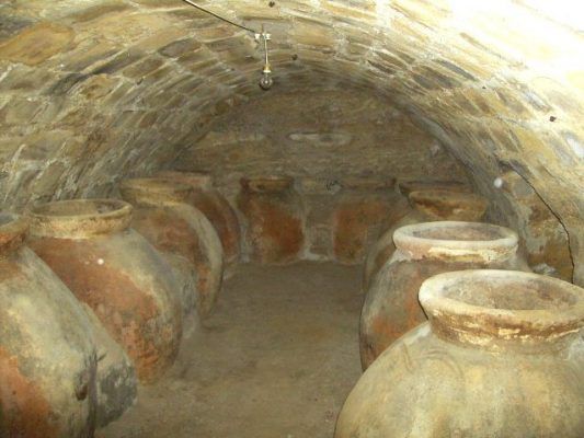 Una cámara subterránea arribadada con numerosas grandes tinajas de barro colocadas a lo largo de las paredes, diseñadas para cómo rebajar el suelo.