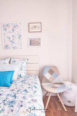 Una habitación ordenadamente dispuesta con paredes de colores pastel, diseñada por Emmme Studio, una cama individual con ropa de cama floral, una silla con una