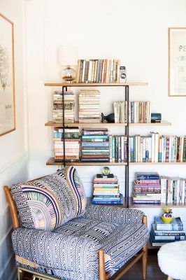 Una acogedora zona de lectura con un sillón estampado y un estante de madera repleto de libros, diseñada siguiendo las últimas tendencias en