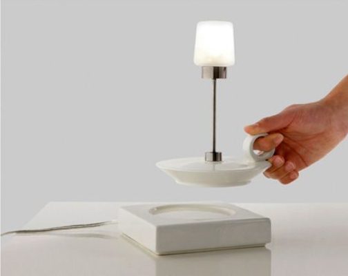 Una persona ajusta una pequeña lámpara de mesa moderna e inalámbrica con un diseño único que integra un asa en su base, perfecta para la decoración