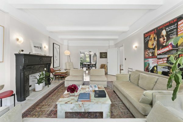 Un salón espacioso y bien iluminado, amueblado con una mezcla de elementos modernos y tradicionales, con un gran cartel de película de Chloë Sevigny en una pared, una mesa de centro de mármol en