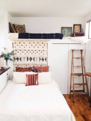 Una acogedora habitación que aprovecha las alturas de la casa, presentando una cama blanca en el nivel del suelo con almohadas estampadas y un litro.