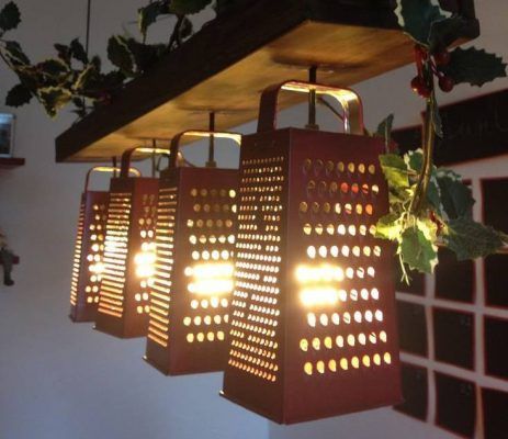Cuatro lámparas colgantes diseñadas para empezar a parecer ralladores de gran tamaño cuelgan del techo, proyectando luces y sombras estampadas en el entorno.