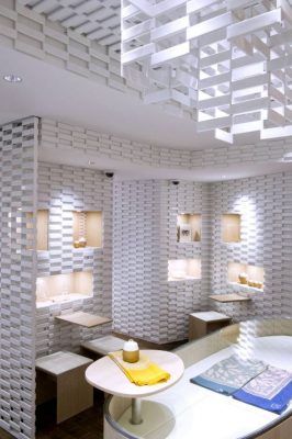 Una moderna cocina con decoración de estantes blancos geométricos creando un efecto de patrón en las paredes y el techo, presentando una mesa de com.