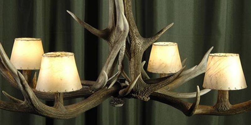 Lámparas de cornamentas con cuatro pantallas contra un fondo de cortina verde, perfectas para una decoración rústica.