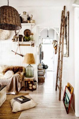 Una acogedora entrada de estilo rústico llena de encanto, decorada con objetos eclécticos, donde destaca una escalera apoyada contra la pared,