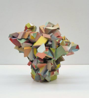 Una exposición de una escultura geométrica multicolor compuesta de numerosos bloques de madera entrelazados.
