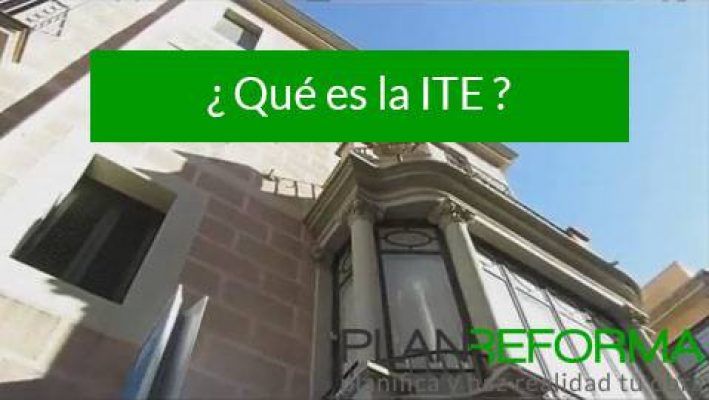 Vista exterior de un edificio con un cartel informativo verde en lo alto que pregunta "¿Qué es la ITE?" (¿Qué es la ITE?) en español, con la parte inferior del cartel que dice "pilar