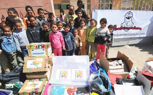 Un grupo de niños y varios adultos parados detrás de cajas de donaciones con una pancarta que decía "Pandas Solidarios" al fondo.
