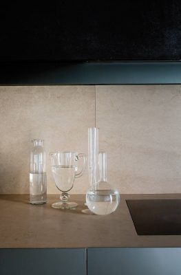 Una colección perfecta armonía de cristalería transparente, incluyendo una botella, una jarra y dos jarrones decorativos, dispuestas en la encimera.